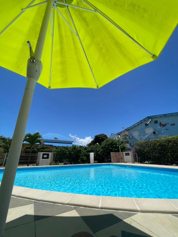 żółty parasol siedzący obok basenu w obiekcie Appartement Coeur de Papillon w mieście Baie-Mahault