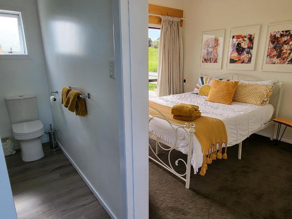 Un dormitorio con una cama con almohadas amarillas y una ventana en Tui Cottage, 