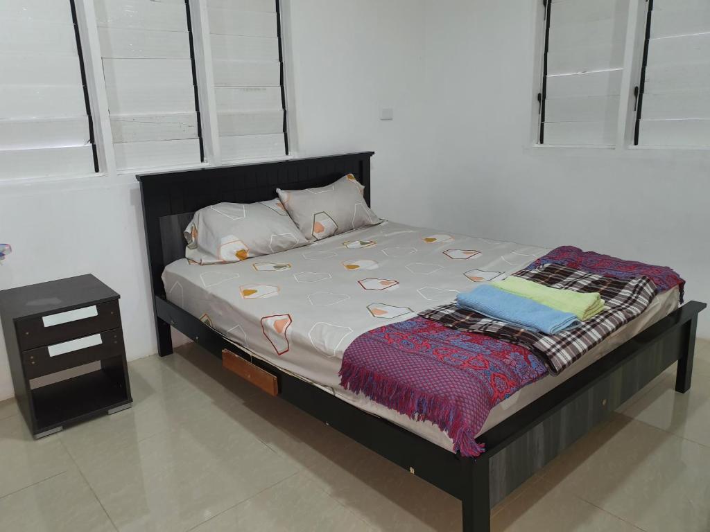 a bed with a black bed frame and a night stand at Single Room with Shared Kitchen and Living Room in Suva