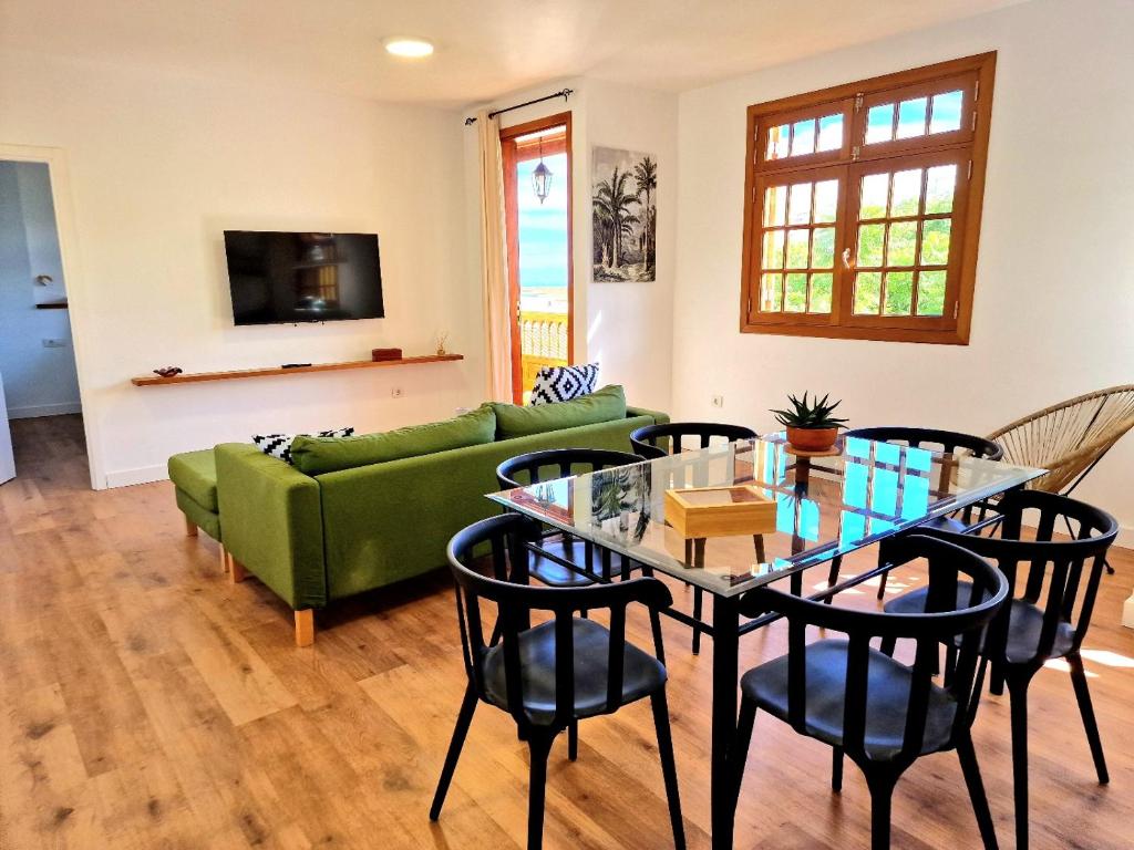 uma sala de estar com uma mesa e um sofá verde em Jacaranda Azul Icod de los Vinos em Icod de los Vinos