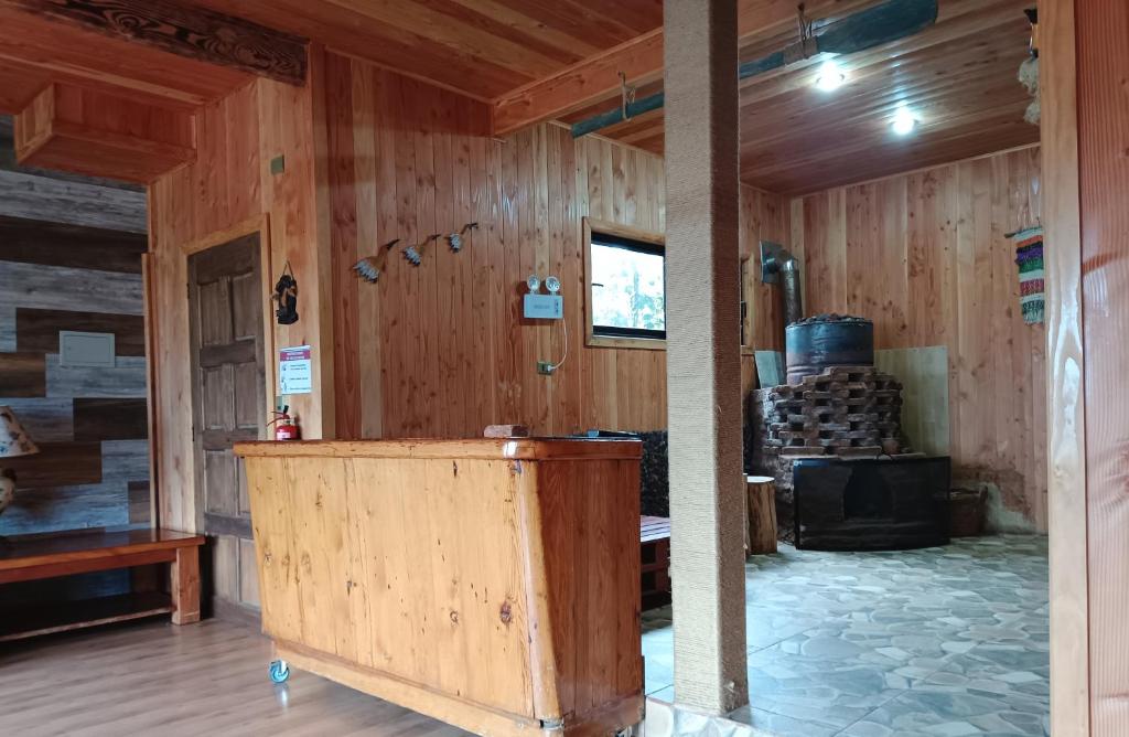 a room with wood paneled walls and a stove in it at Hostel Calafquen Coñaripe in Coñaripe