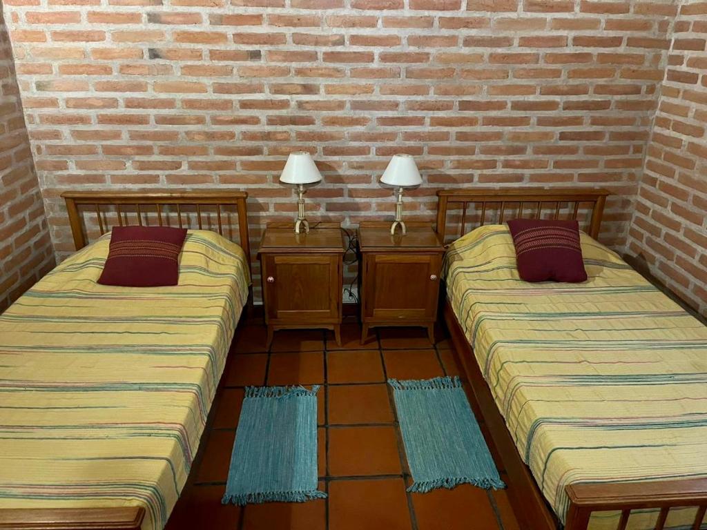 two beds in a room with a brick wall at Pintoresca casa con pileta in Yala