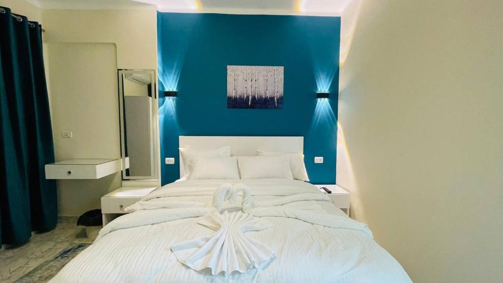 a bedroom with a large white bed with a blue wall at Cozy apartment in down town in Cairo