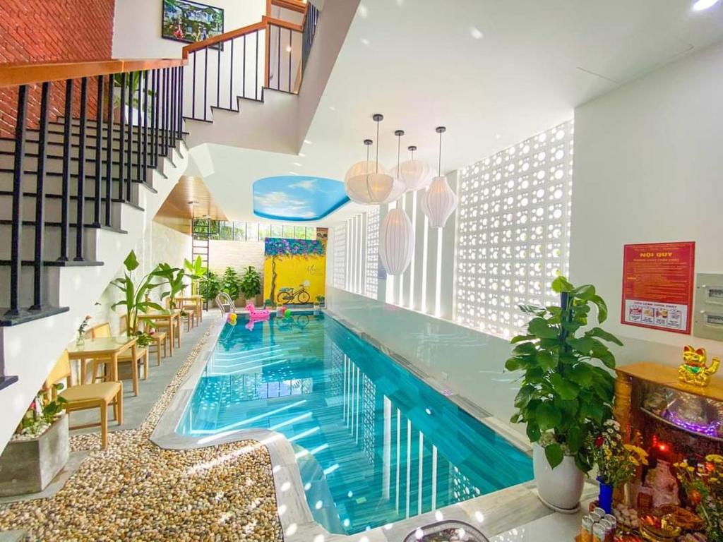 a large swimming pool in a house with a staircase at Mint Hoi An Villa in Hoi An