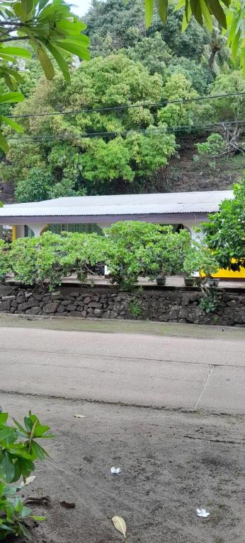 un banco junto a una carretera con flores y árboles en Penu Maurua lodge en Te-Fare-Arii