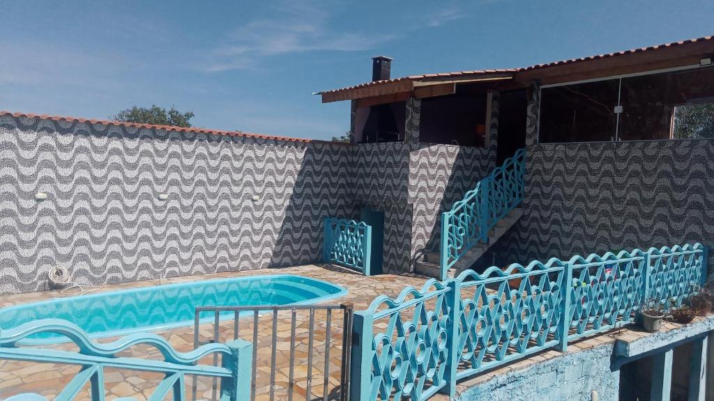 - une piscine avec des chaises bleues à côté d'un bâtiment dans l'établissement Casa com piscina, à Mairiporã