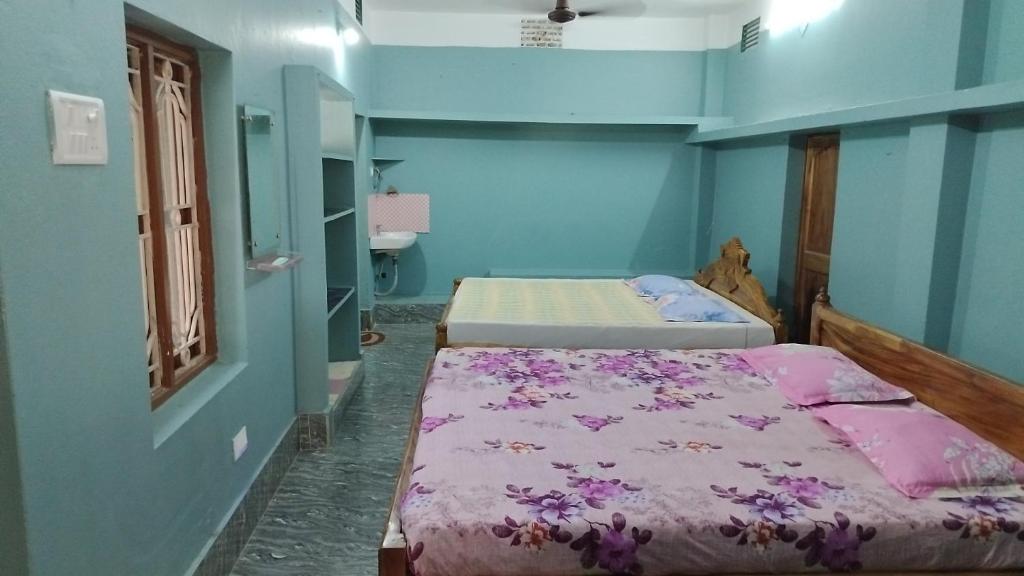 two beds in a room with blue walls at Gourinandan lodge in Puri