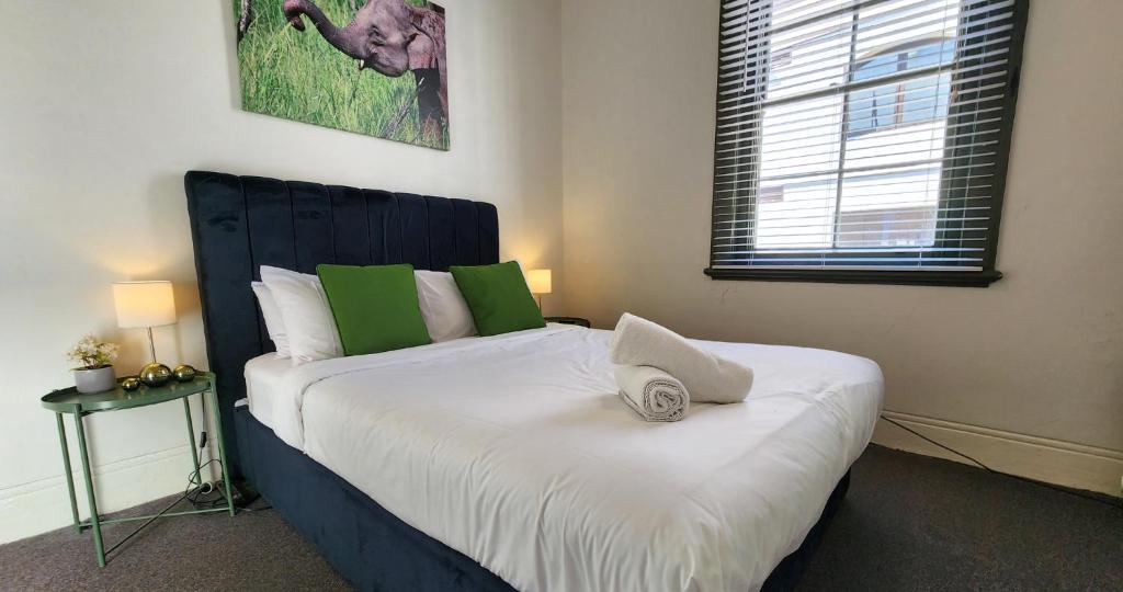 1 dormitorio con 1 cama grande con almohadas blancas y verdes en Discover The Rocks - Historical Terrace House, en Sídney