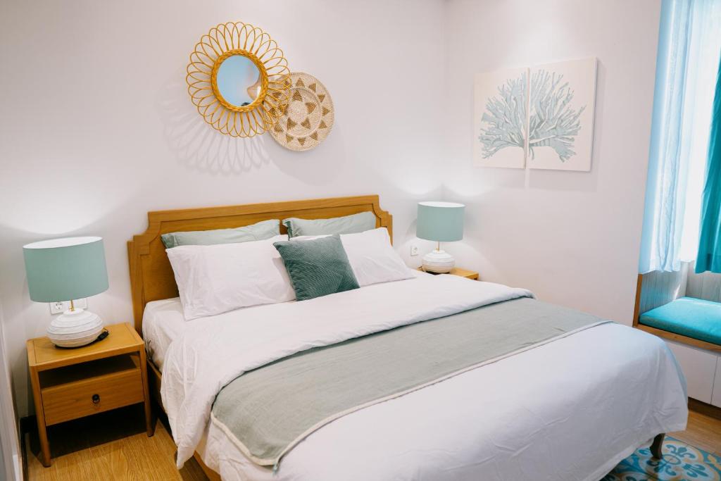 a bedroom with a bed with white sheets and a mirror at Casa Amarta Canggu - Boutique Lofts & Detox SPA in Canggu