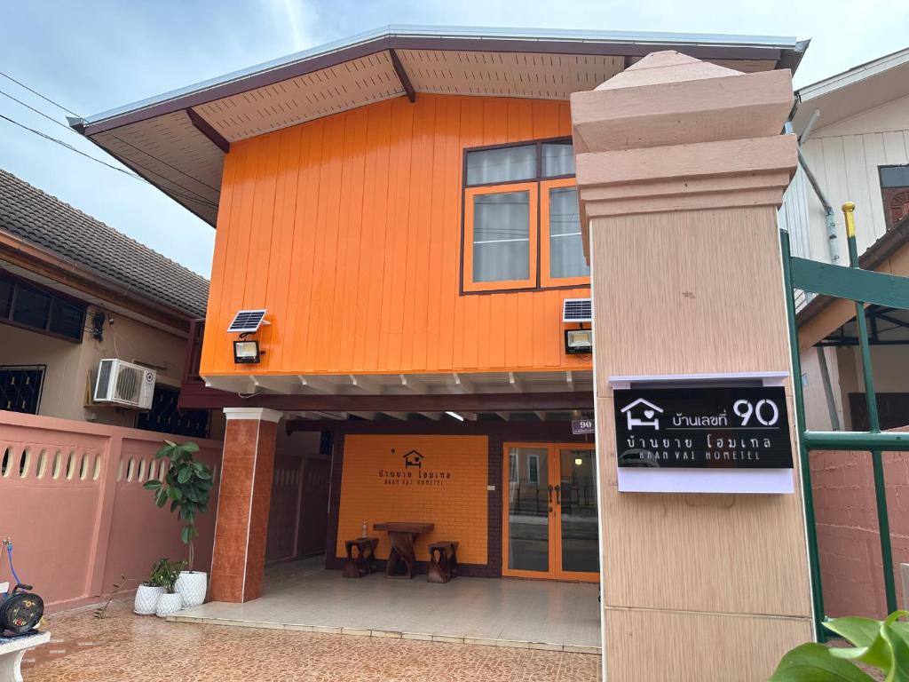 een oranje gebouw met een bord ervoor bij บ้านยายโฮมเทล Baan yai hometel in Nakhon Phanom