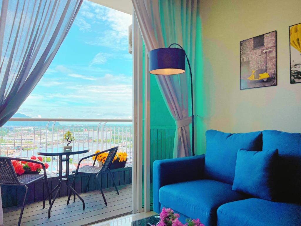 sala de estar con sofá azul y ventana grande en Ipoh Town Family Suite w Balcony[8pax]FREE Parking, en Ipoh