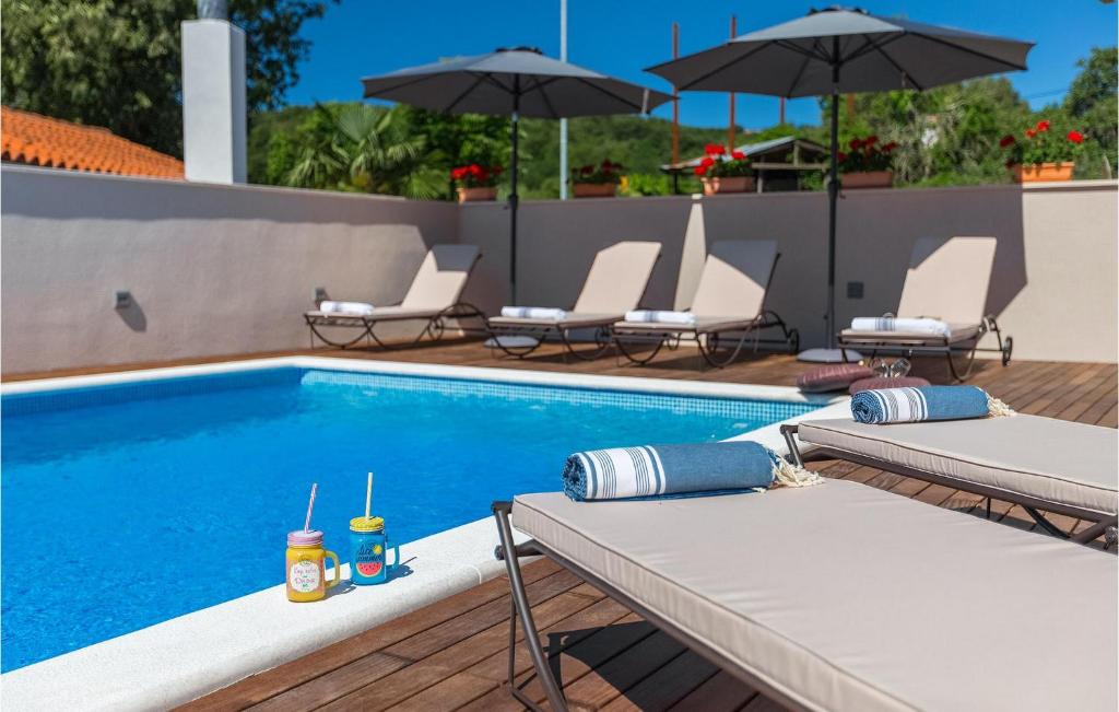 a swimming pool with lounge chairs and umbrellas next to it at Villa Unka in Potpićan