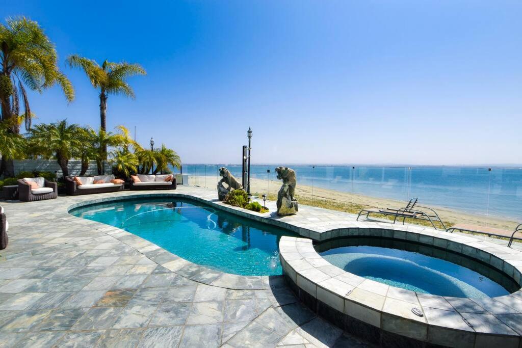 a swimming pool next to a beach with palm trees at Private Beach front 4bed 4bath pool and spa house in San Diego