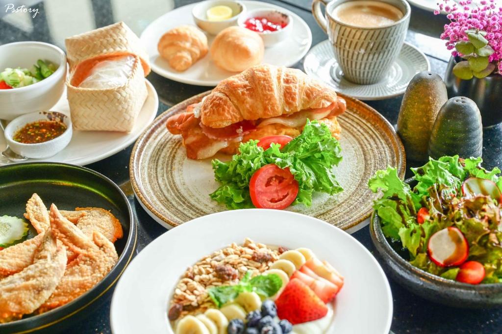 A breakfast spread includes pastries, sandwiches, fruit, salads and hot drinks.