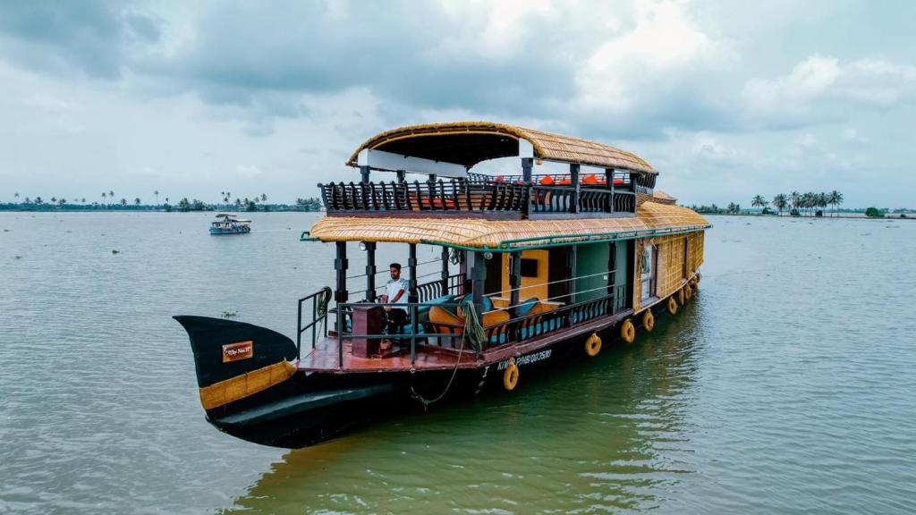 a ferry boat in the water on a river at Why Not Houseboat in Alleppey