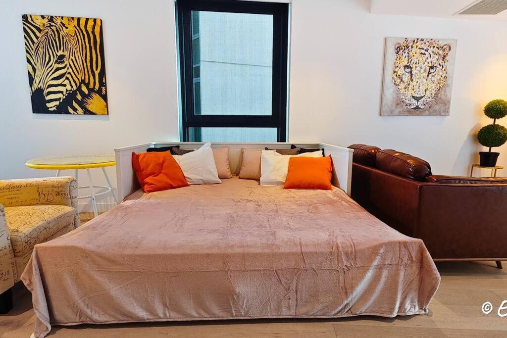 een slaapkamer met een bed met oranje kussens en een bank bij Southbank 23F 1BR 4Guest City Skyline Pool & Gym in Melbourne