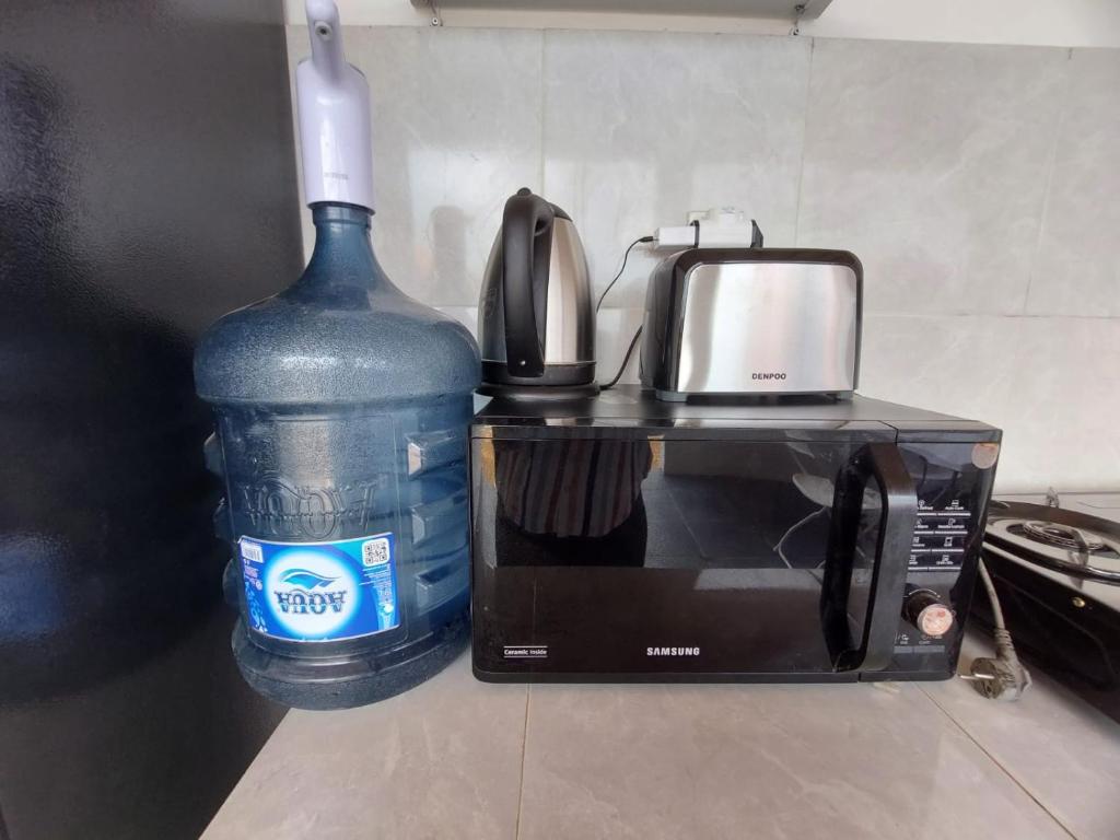 a bottle of water next to a toaster and a microwave at Les Chalets Pecatu in Uluwatu