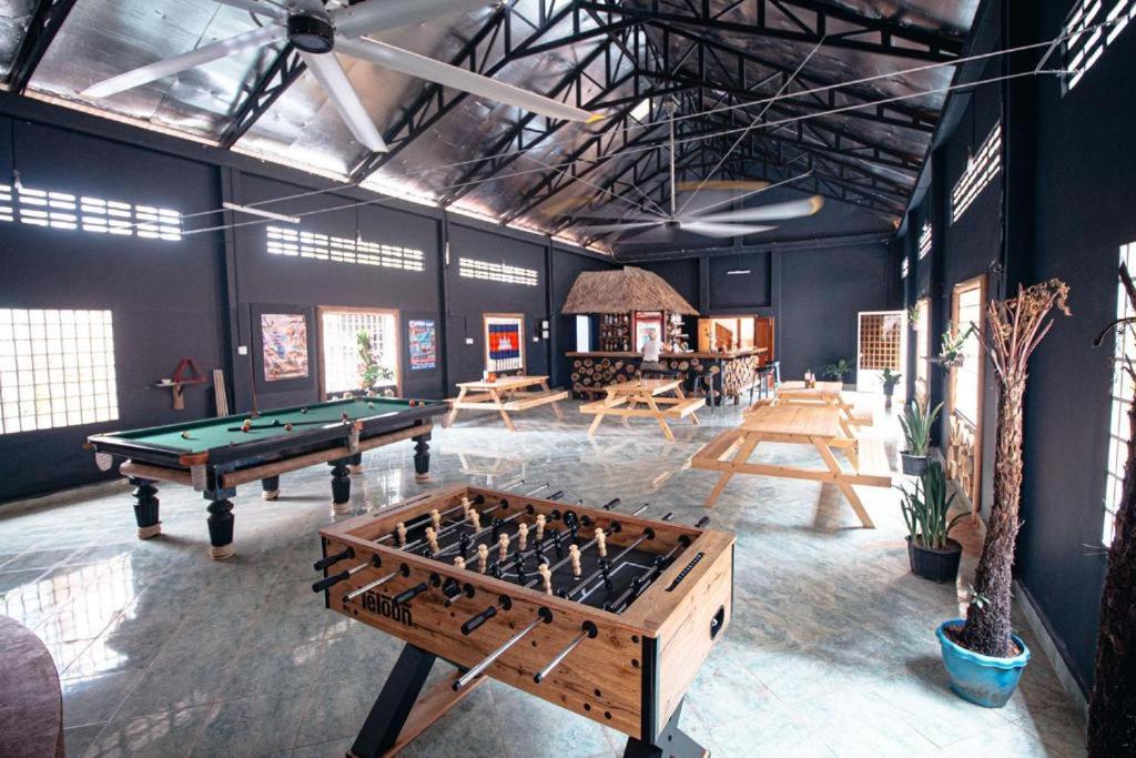 a room with a pool table and several tables at The Pig Pen Hostel & BBQ in Kampot