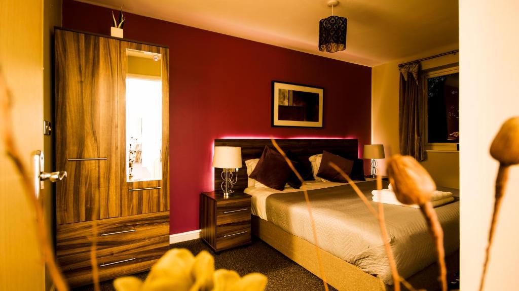 SOUTHAMPTON Central Apartments - Wise Stays في ساوثهامبتون: غرفة نوم بسرير بجدار احمر