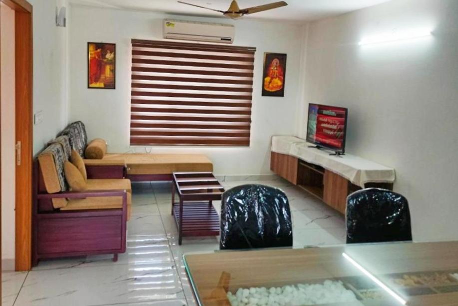 sala de estar con sofá, mesa y sillas en Luxurious Apartment with a pool and gym near Trivandrum railway station en Thiruvananthapuram