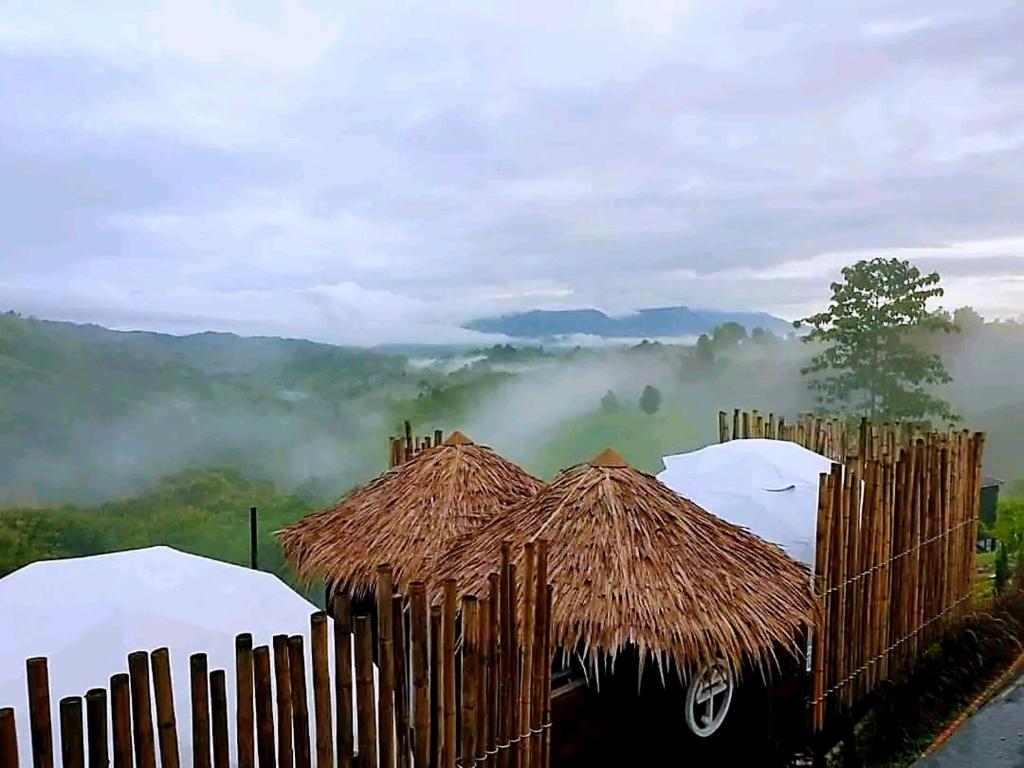 a view of a misty mountain with a straw hut at Black Diamond Camping in Khao Kho