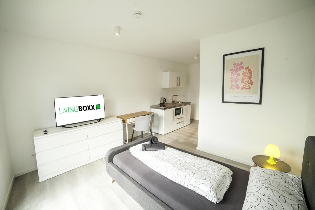 een witte woonkamer met een bank en een tv bij Livingboxx Karlsruhe in Rheinstetten