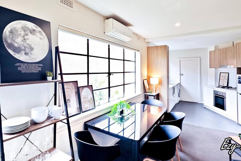 eine Küche mit einem Glastisch und schwarzen Stühlen in der Unterkunft MCG 1BR Apartment For Family in Melbourne