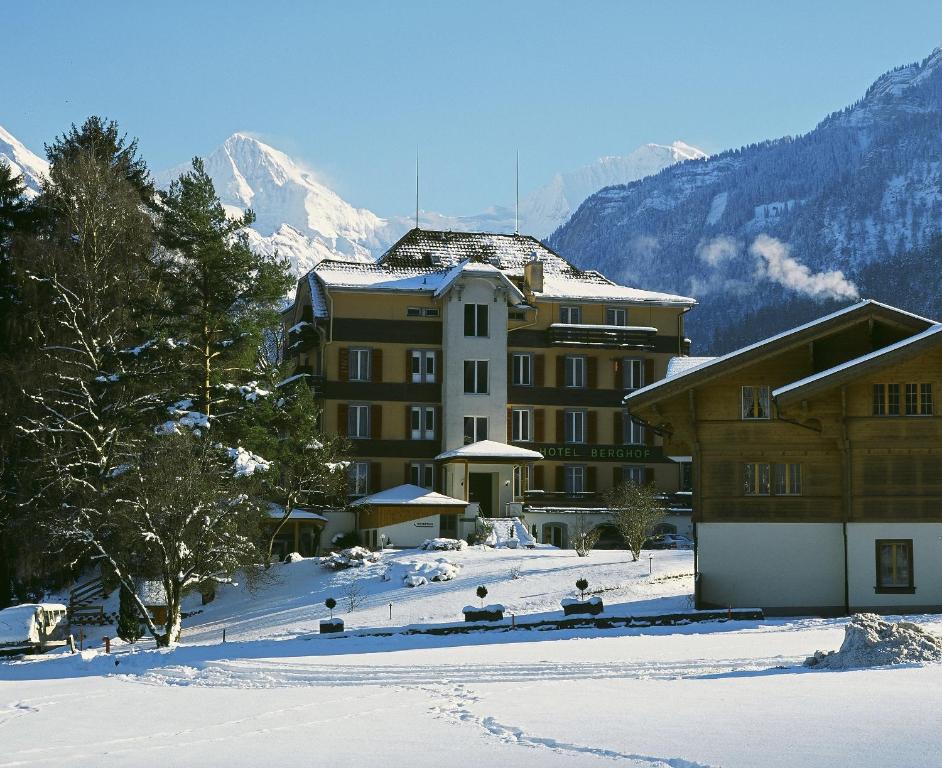 a building in the snow next to a mountain at Hotel Berghof Amaranth in Wilderswil