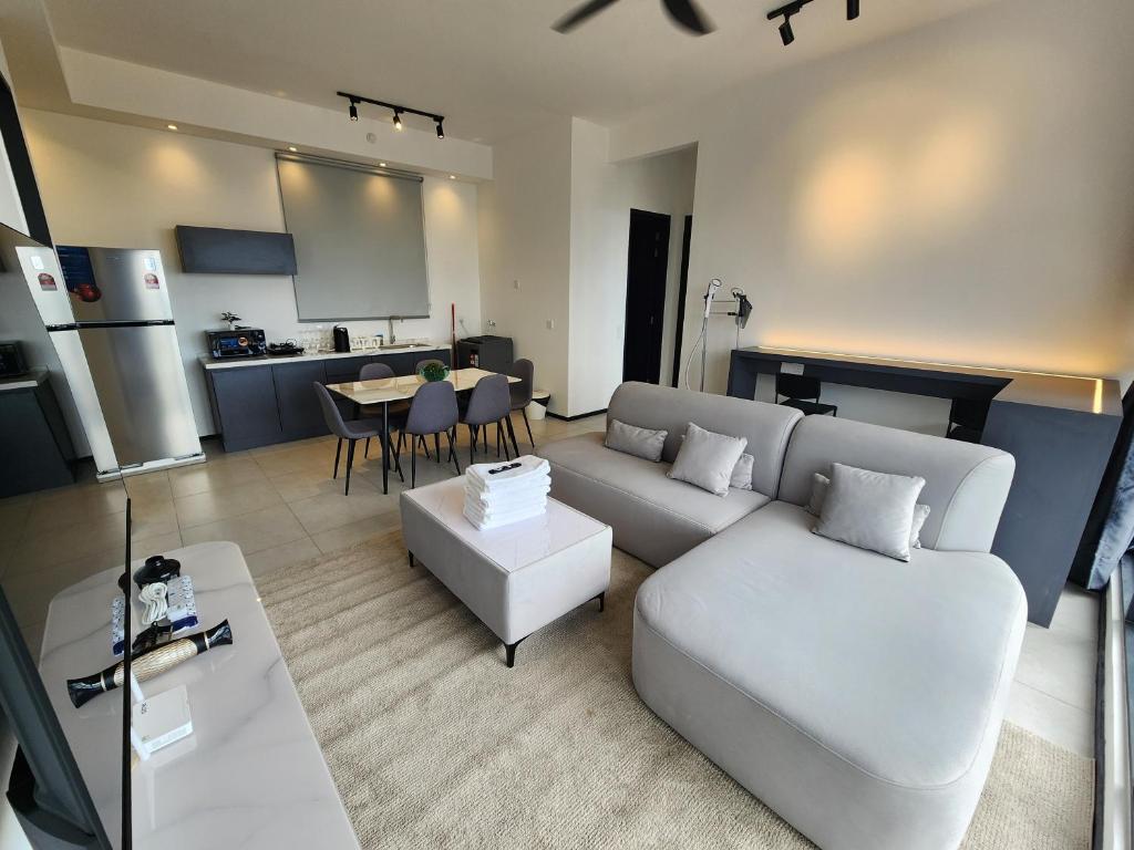 Executive Urban Suites - George Town @ Penang في Jelutong: غرفة معيشة مع أريكة بيضاء ومطبخ