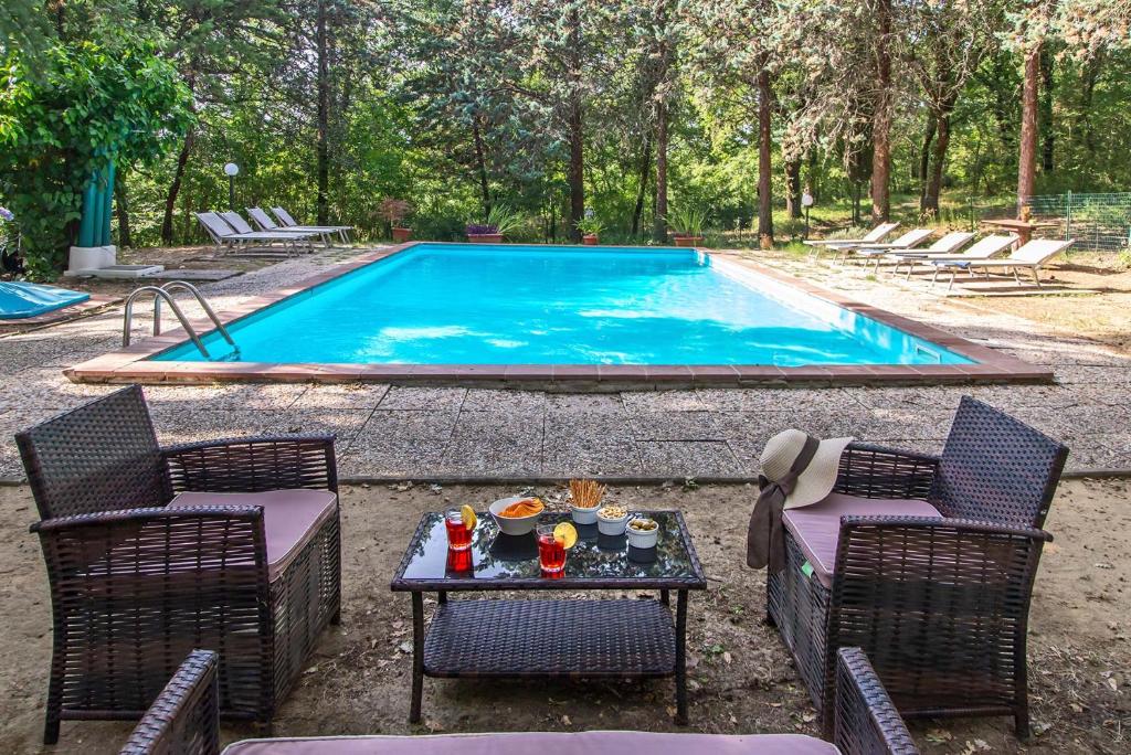 uma piscina com duas cadeiras e uma mesa com comida em Agriturismo Villa Alari em Cetona