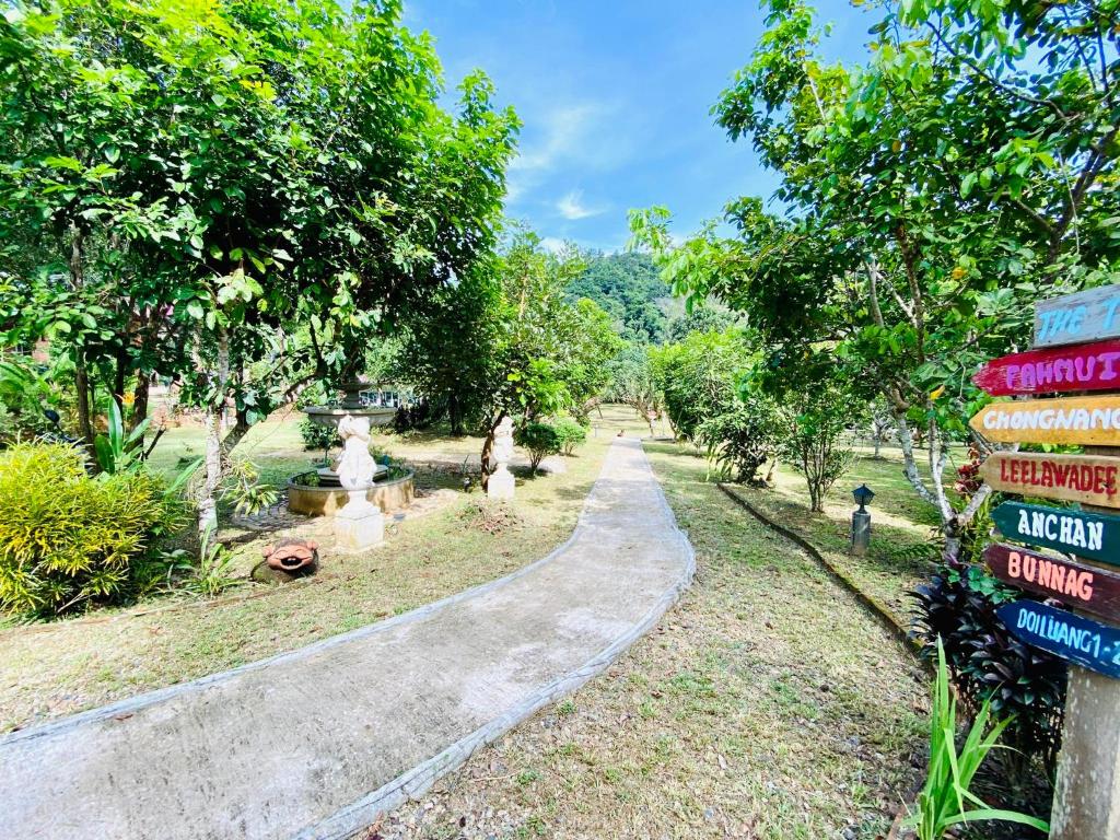 a winding path in a park with trees and a sign at At Home Chiang Dao, Pooch Lovers in Ban Tham