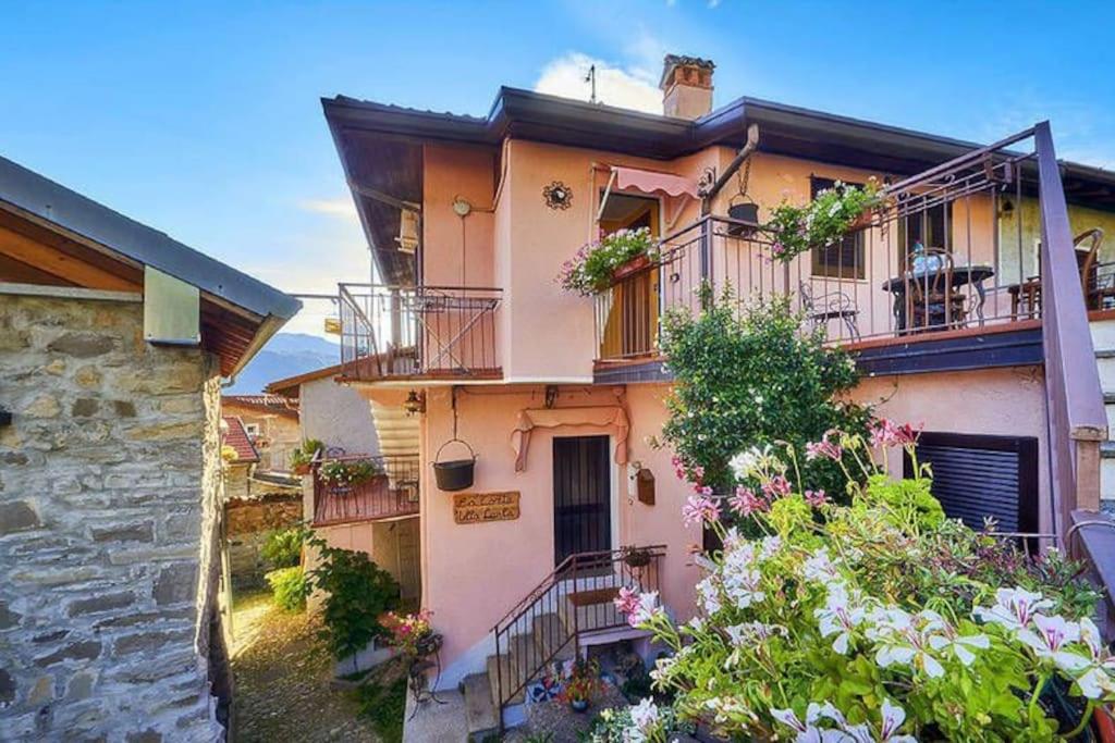 a building with balconies and flowers in front of it at LA CORTE DELLA CARLA - cozy home in the old court in Lierna