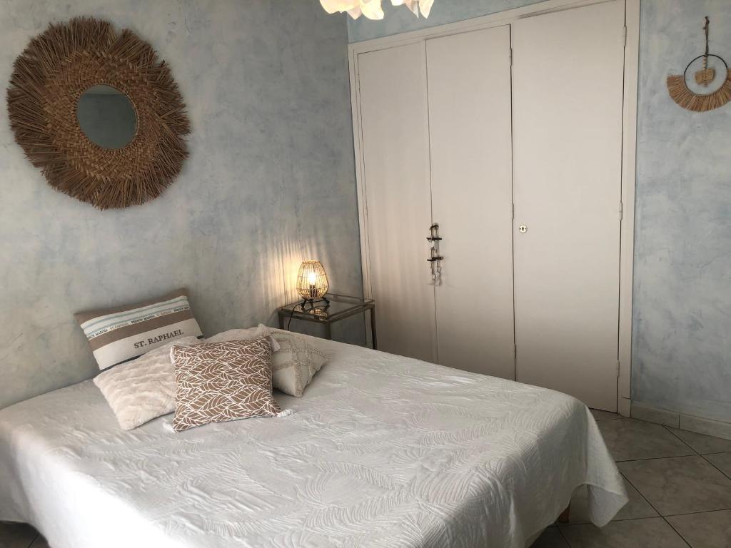 een slaapkamer met een wit bed en een spiegel bij Appartement Vue Mer 75 m2 in Saint-Raphaël