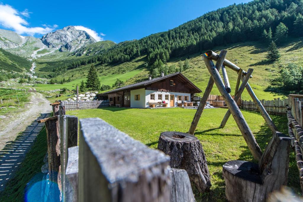 a house in the mountains with a fence at Alm Chalet Oberkofl in San Giacomo