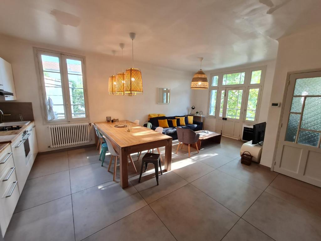 eine Küche und ein Wohnzimmer mit einem Holztisch und Stühlen in der Unterkunft Appart Magnolia Villeneuve les Avignon - Provence in Villeneuve-lès-Avignon