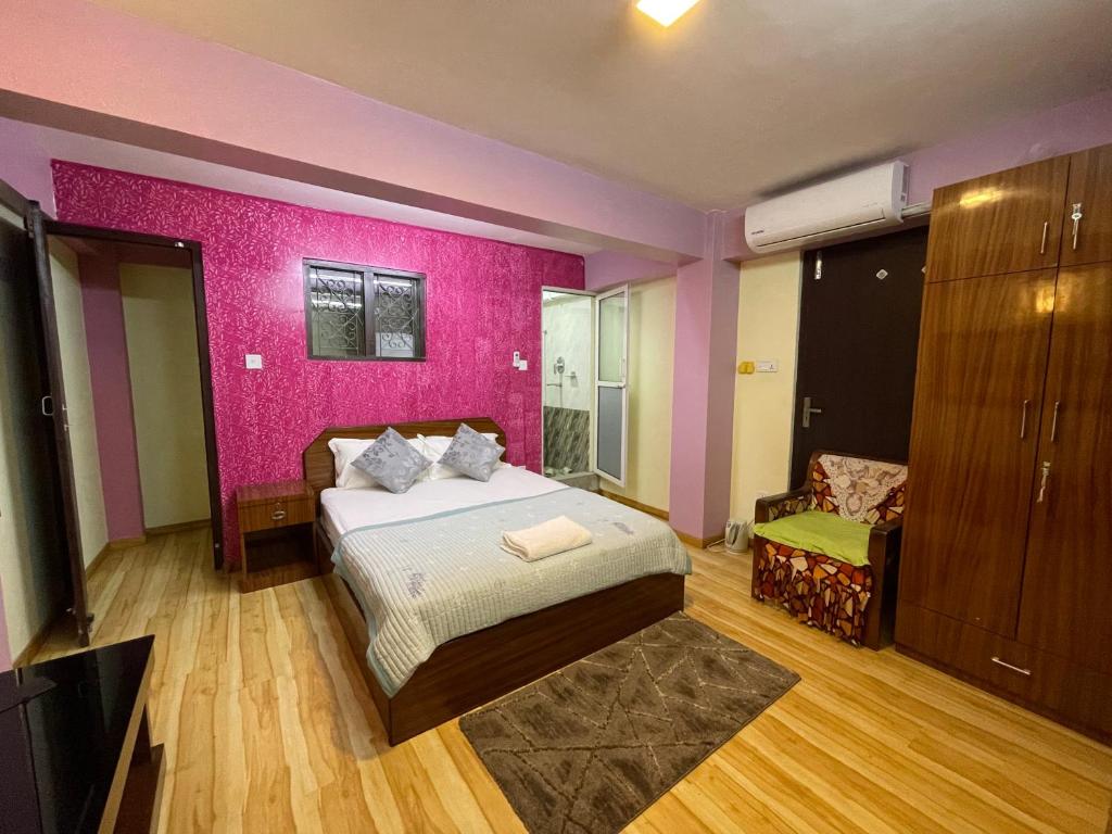 パタンにあるKaji Homestayのピンクの壁、ベッド1台付きのベッドルーム1室