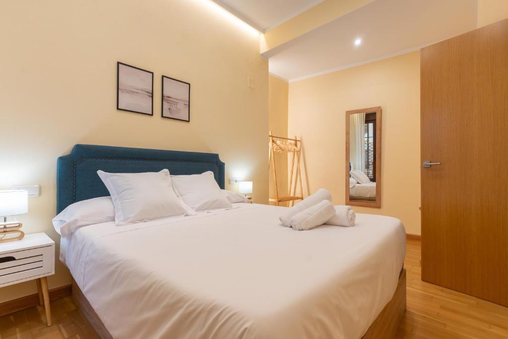 um quarto com uma grande cama branca e uma cabeceira azul em APARTAMENTO PUERTA DE CÓRDOBA- Exterior con balcones em Córdoba