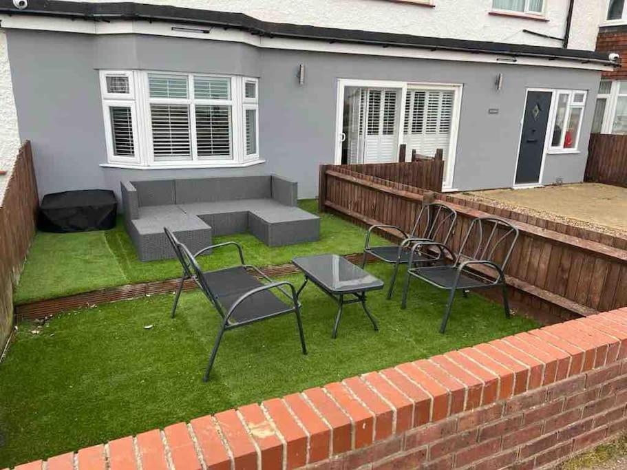 a backyard with two chairs and a table and a bench at A Lovely 2 bedroom ground floor flat, with parking in Walton-on-the-Naze