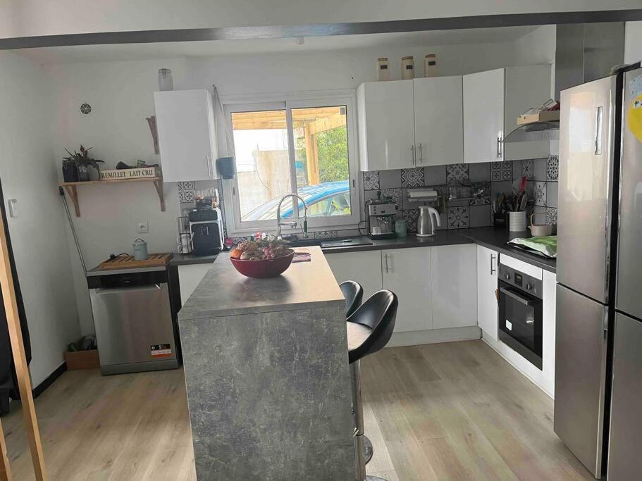 a large kitchen with white cabinets and a counter top at Villa Bois Court 3 chambres in Le Tampon