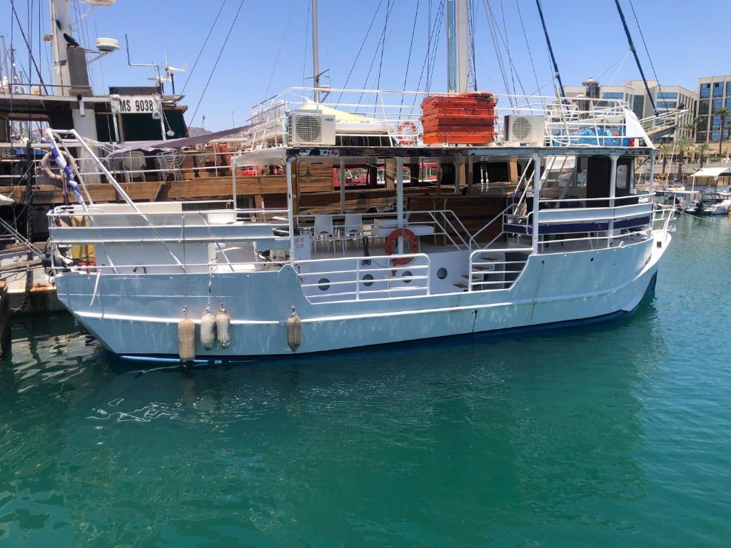 a white boat is docked in the water at הספינה של אריק in Eilat