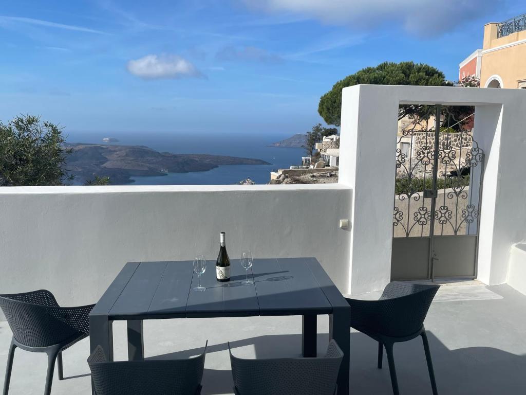 a table with a bottle of wine on a balcony at Villa DALI Danae in Fira