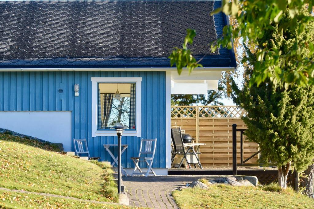 ein blaues Haus mit Stühlen auf der Veranda in der Unterkunft Sjöstuga/gästhus i skärgården. in Åkersberga