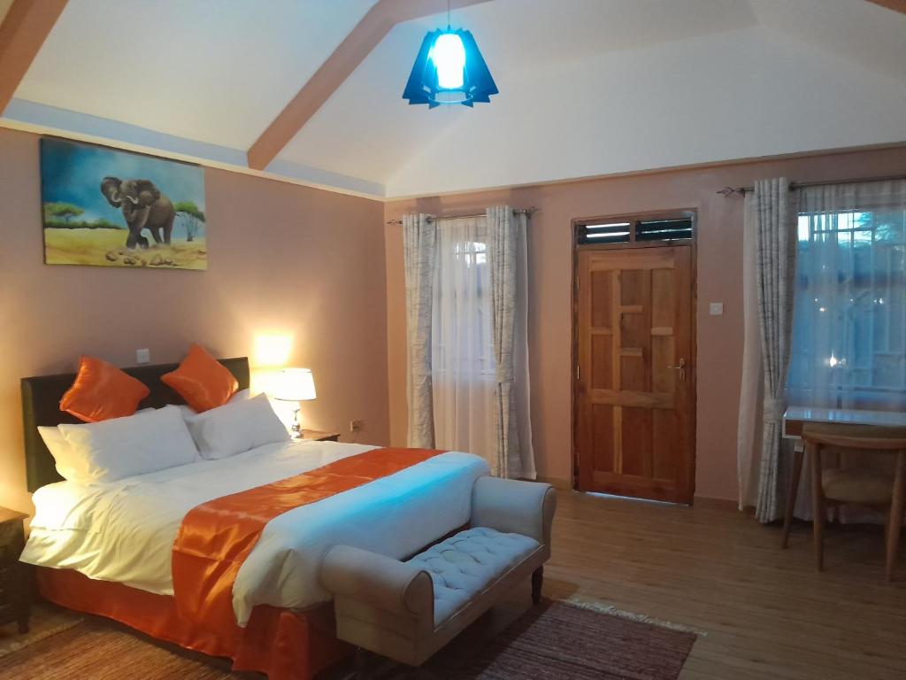 um quarto com uma cama, uma cadeira e uma secretária em PENETY AMBOSELI RESORT em Amboseli