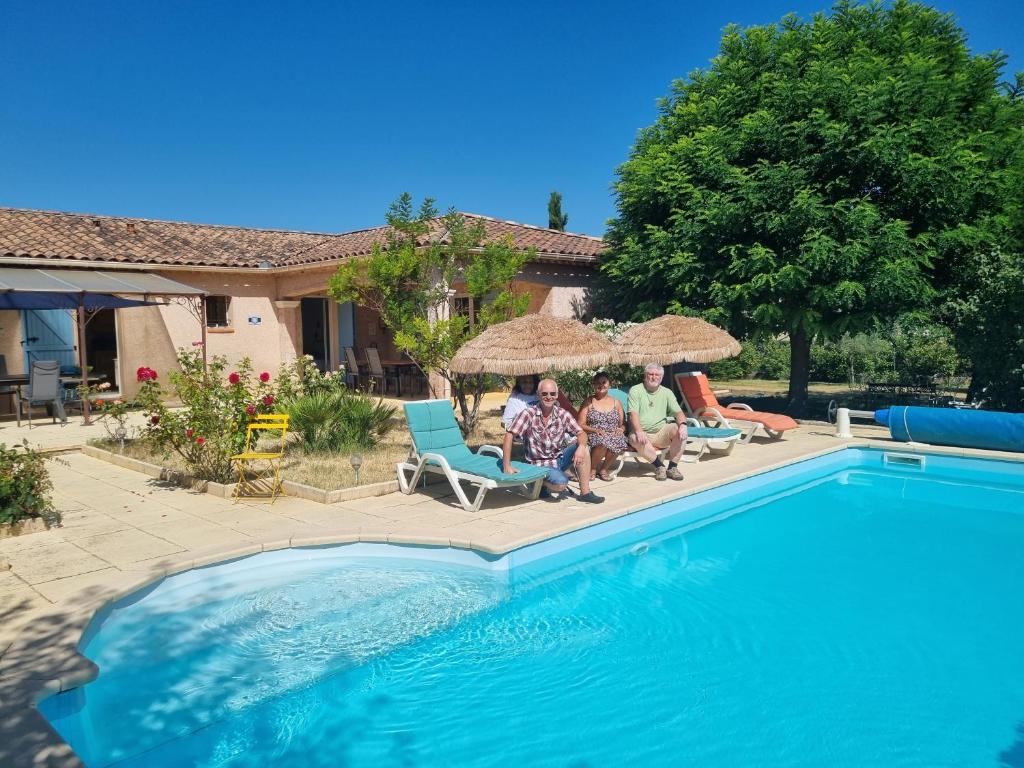 un grupo de personas sentadas junto a una piscina en Villa de charme Mas de la Cigaline & chambres d'hôtes chez Dany 83, en Garéoult