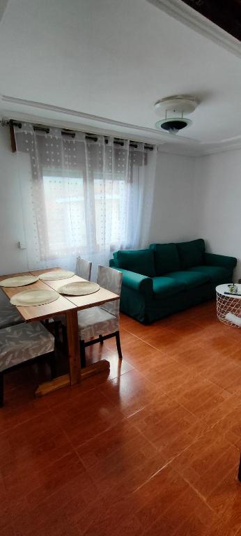 - un salon avec une table et un canapé vert dans l'établissement Apartamento Ortuella, à Ortuella