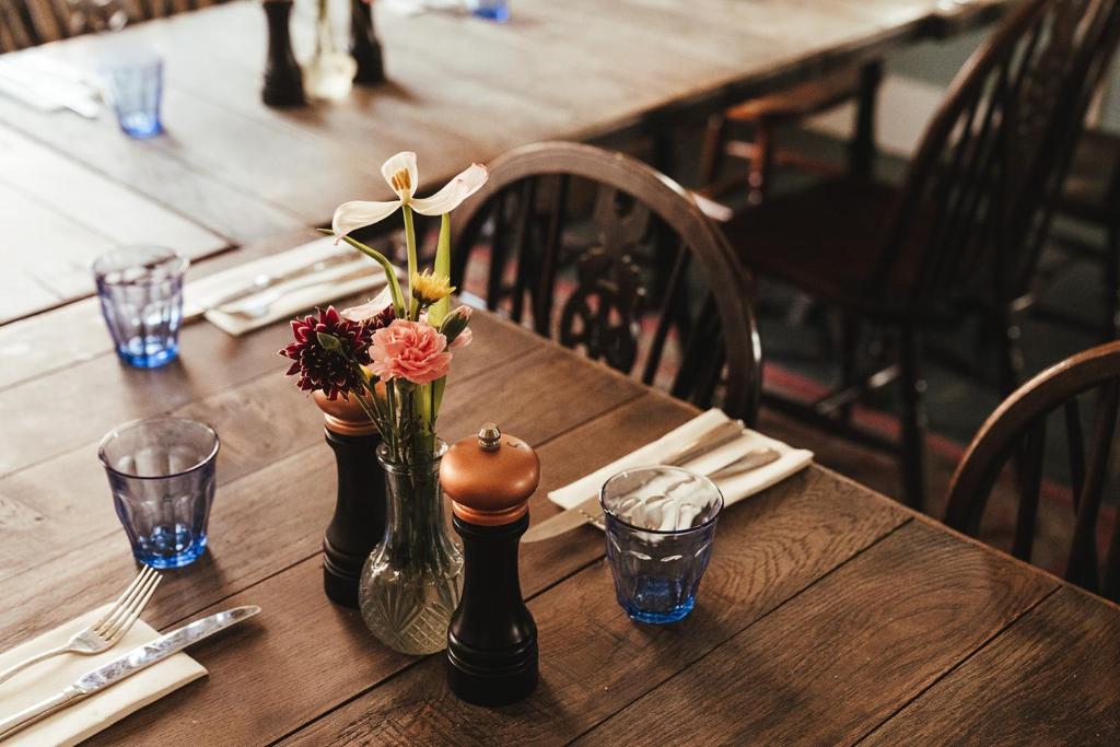 a wooden table with a vase with flowers in it at The Ship Inn in Rye