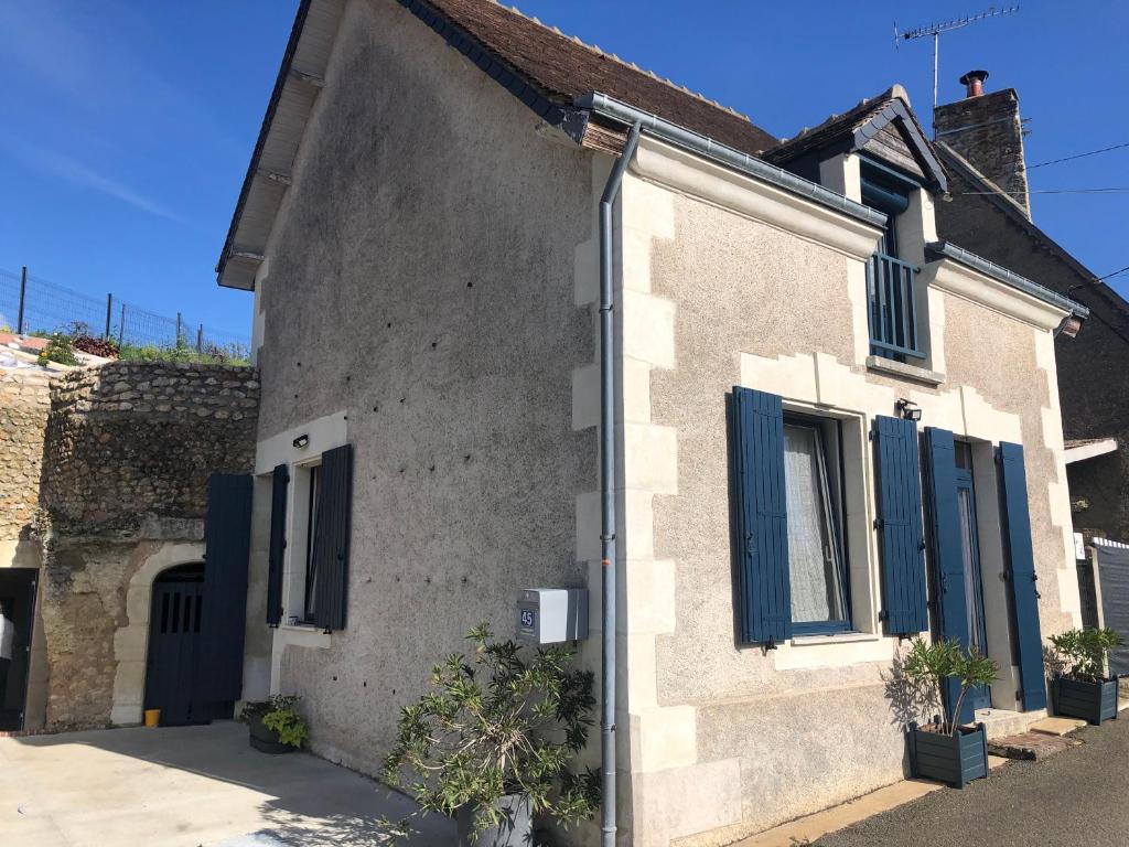 a white house with blue shutters on it at La cav ô lauriers in Lunay