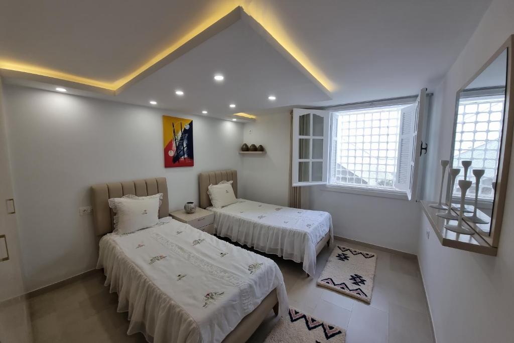 two beds in a room with white walls and windows at Appartement de luxe près de la mer in Nabeul