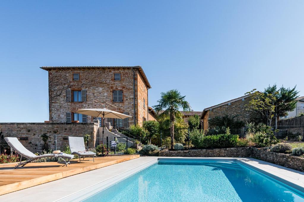 eine Villa mit einem Pool vor einem Gebäude in der Unterkunft Maison de Pagneux in Lachassagne