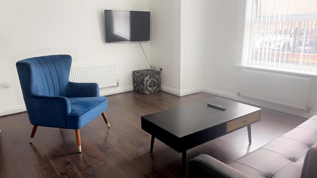ein Wohnzimmer mit einem blauen Stuhl und einem Couchtisch in der Unterkunft 2 bedroom apartment, free parking & WIFI near City Centre in Manchester